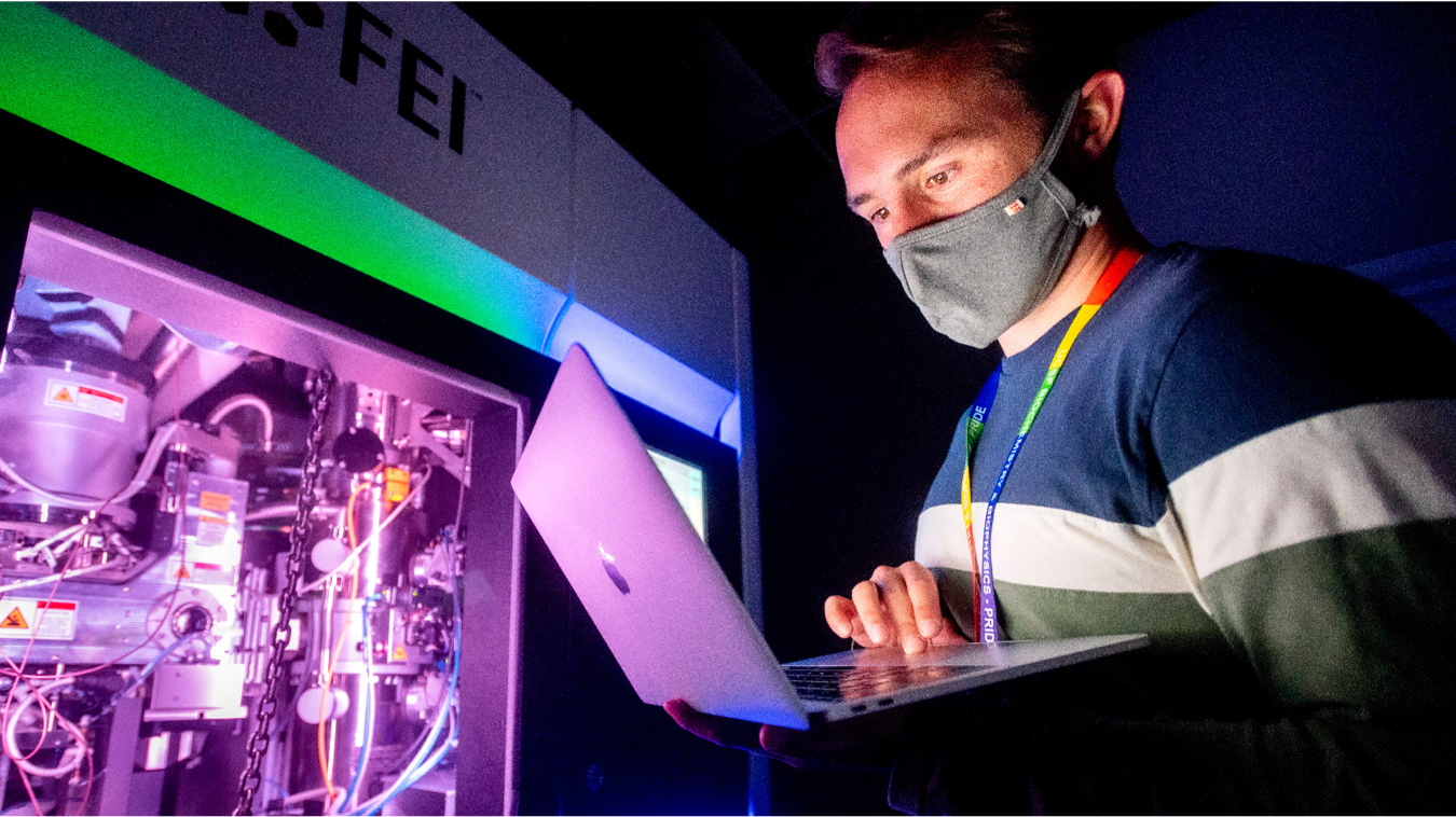 man with face covering working on a laptop